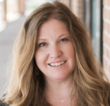 A therapist smiling in front of a brick wall. A therapist smiling in front of a brick wall.